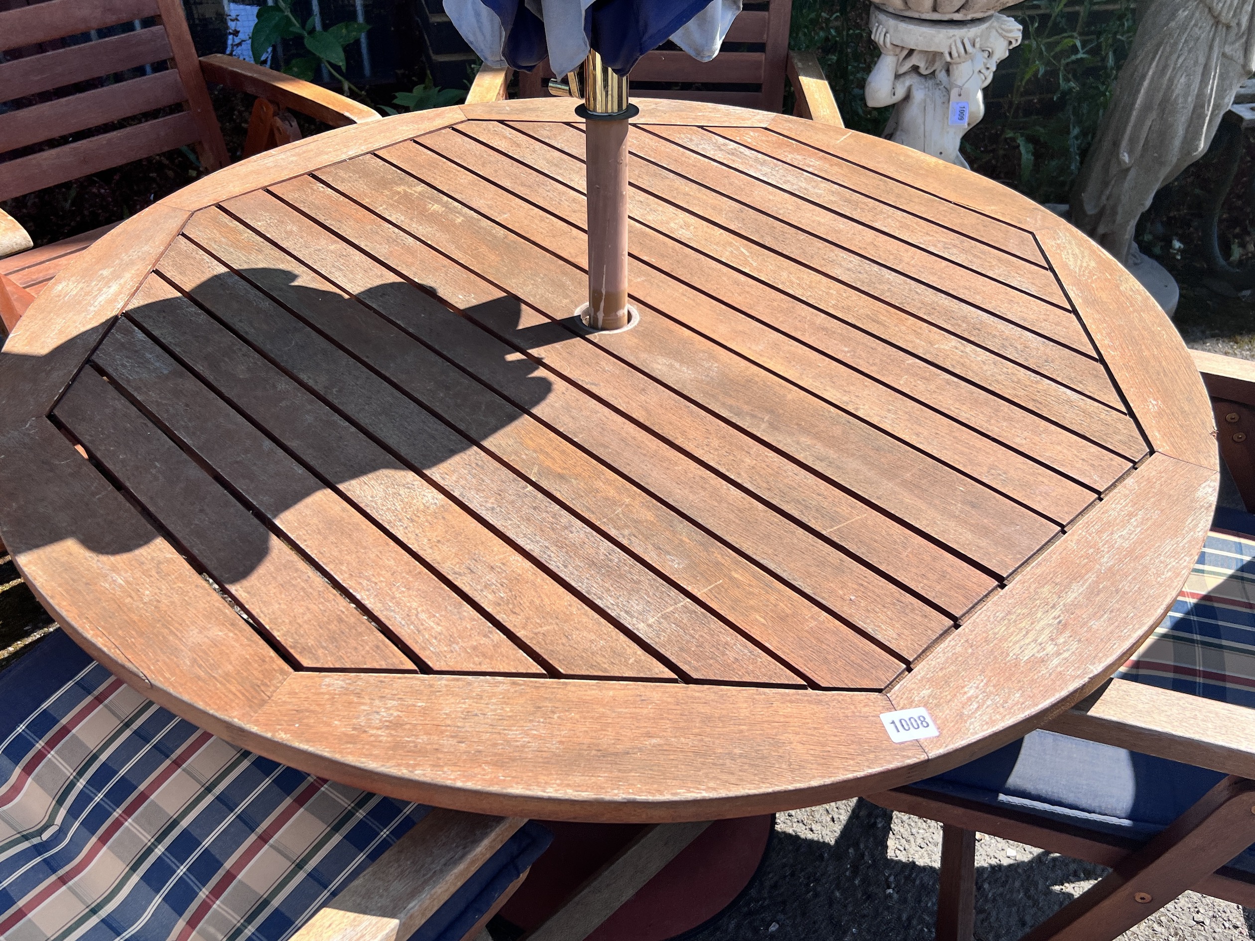 A Royal Craft teak folding table and four chairs with two cushions, parasol and cast metal base, table 110cm diameter, height 74cm.